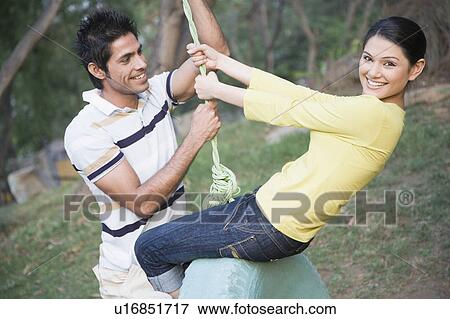 Young couple swinging on a tire swing View Large Photo Image Stock Photo - Young couple swinging on a tire swing. Fotosearch