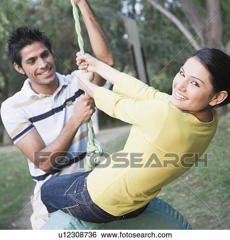 Young couple swinging on a tire swing and smiling View Large Photo Image Stock Photograph - Young couple swinging on a tire swing and smiling. Fotosearch