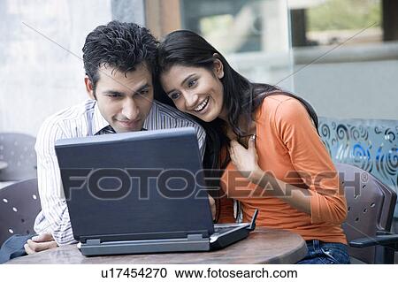 Young couple using a laptop and smiling View Large Photo Image Stock Image - Young couple using a laptop and smiling. Fotosearch