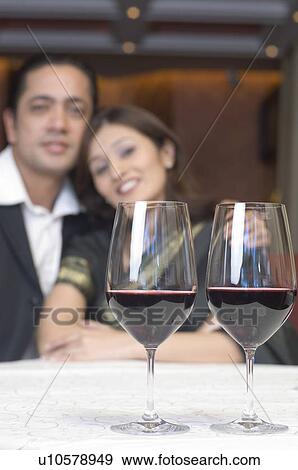 Close-up of two glasses of wine on a table in front of a couple View Large Photo Image Stock Photo - Close-up of two glasses of wine on a table in front of a couple. Fotosearch