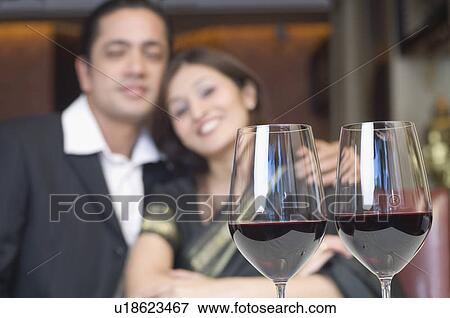 Close-up of two glasses of wine on a table in front of a couple View Large Photo Image Stock Photo - Close-up of two glasses of wine on a table in front of a couple. Fotosearch
