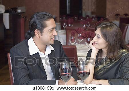 Stock Photography - Mid adult man with a young woman looking at each other and sitting in a restaurant. Fotosearch
