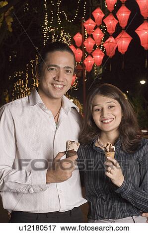 Portrait of a couple holding ice-cream cones and smiling View Large Photo Image Stock Photo - Portrait of a couple holding ice-cream cones and smiling. Fotosearch