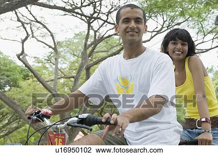 Portrait of a young couple riding a bicycle and smiling View Large Photo Image Stock Image - Portrait of a young couple riding a bicycle and smiling . Fotosearch