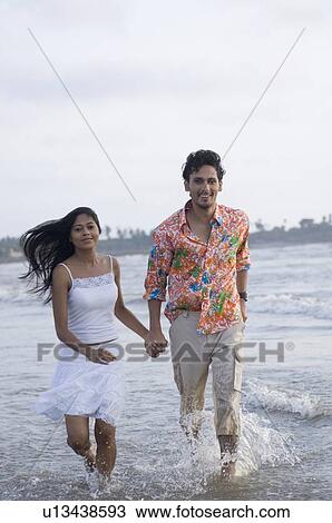 Portrait of a young couple running with holding hands on the beach View Large Photo Image Stock Image - Portrait of a young couple running with holding hands on the beach. Fotosearch