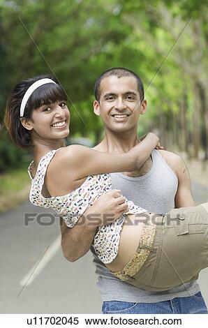 Portrait of a young man carrying a young woman in his arms View Large Photo Image Stock Photography - Portrait of a young man carrying a young woman in his arms. Fotosearch