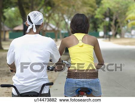 Rear view of a young couple riding bicycles View Large Photo Image Stock Image - Rear view of a young couple riding bicycles. Fotosearch