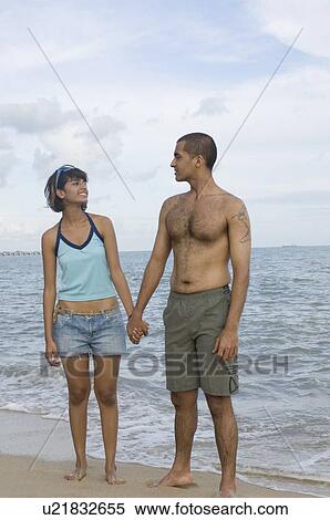 Young couple standing on the beach holding hands View Large Photo Image Stock Photography - Young couple standing on the beach holding hands. Fotosearch