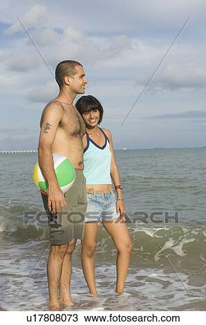 Young couple standing on the beach with a beach ball and smiling View Large Photo Image Stock Image - Young couple standing on the beach with a beach ball and smiling. Fotosearch