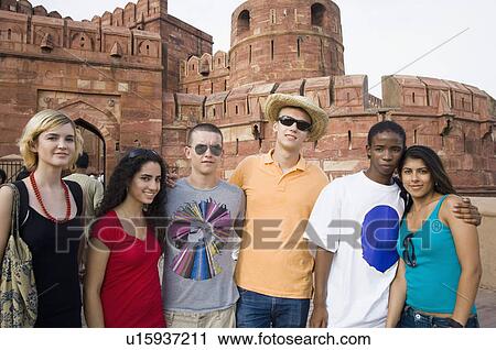 Stock Image - Portrait of a group of friends standing in front of a mausoleum, Taj Mahal, Agra, Uttar Pradesh, India. Fotosearch