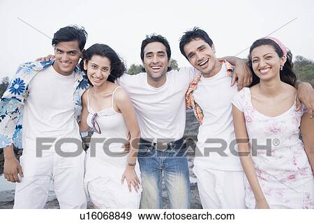 Stock Photo - Portrait of three young men and two young women standing together and smiling. Fotosearch