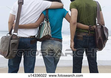Rear view of a woman with her arms around two men View Large Photo Image Stock Image - Rear view of a woman with her arms around two men. Fotosearch