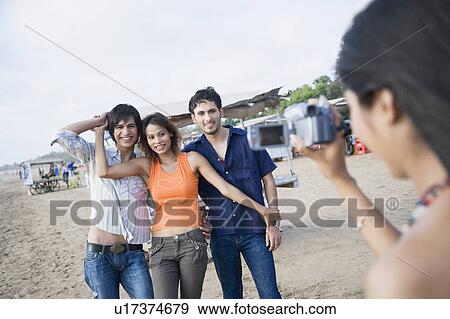 Rear view of a young woman filming her friends with a home video camera View Large Photo Image Stock Photo - Rear view of a young woman filming her friends with a home video camera. Fotosearch