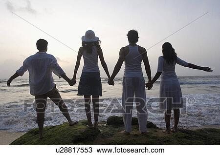 Rear view of two young couples holding hands of each other View Large Photo Image Stock Image - Rear view of two young couples holding hands of each other. Fotosearch
