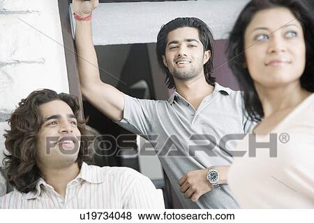 Stock Photo - Two young men and a young woman smiling. Fotosearch