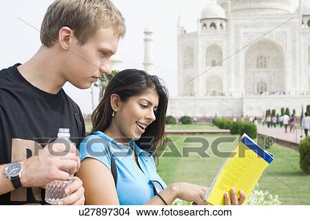 Picture - Close-up of a young couple reading a guidebook in front of a mausoleum, Taj Mahal, Agra, Uttar Pradesh, India. Fotosearch