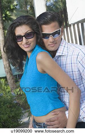 Stock Image - Close-up of a young couple standing together and smiling. Fotosearch