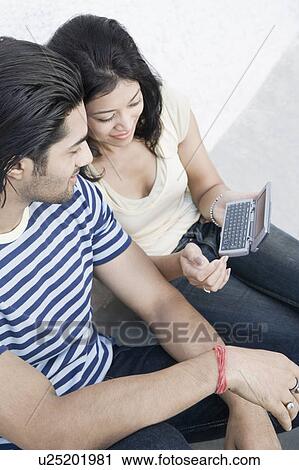 High angle view of a young couple looking at a mobile phone and smiling View Large Photo Image Stock Image - High angle view of a young couple looking at a mobile phone and smiling. Fotosearch