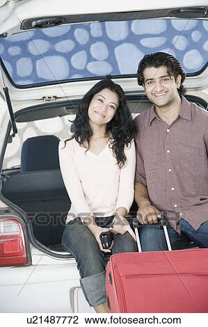 Portrait of a young couple sitting in a car trunk and smiling View Large Photo Image Stock Image - Portrait of a young couple sitting in a car trunk and smiling. Fotosearch
