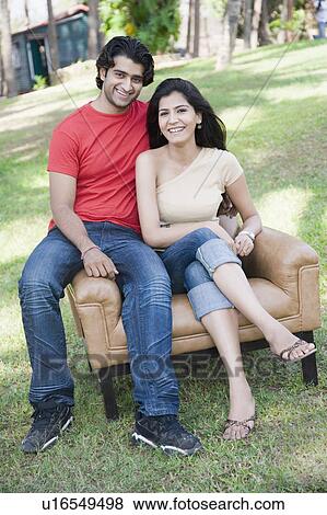 Portrait of a young couple sitting in an armchair in a park and smiling View Large Photo Image Stock Photo - Portrait of a young couple sitting in an armchair in a park and smiling. Fotosearch