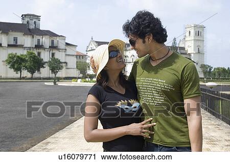 Stock Image - Young couple embracing each other in front of a cathedral, Se Cathedral, Goa, India. Fotosearch