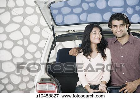 Young couple sitting in a car trunk and smiling View Large Photo Image Stock Photo - Young couple sitting in a car trunk and smiling. Fotosearch