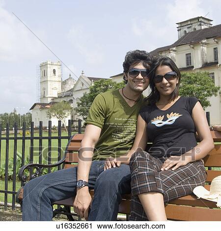 Young couple sitting on a bench and a cathedral in the background, Se Cathedral, Goa, India View Large Photo Image Stock Image - Young couple sitting on a bench and a cathedral in the background, Se Cathedral, Goa, India. Fotosearch