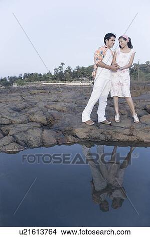 Young couple standing on rocks with holding their hands View Large Photo Image Picture - Young couple standing on rocks with holding their hands. Fotosearch