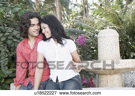 Stock Photo - Young man with his arm around a young woman and smiling. Fotosearch