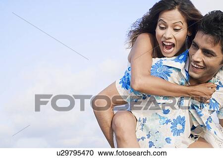 Close-up of a young woman riding piggyback on a young man View Large Photo Image Stock Image - Close-up of a young woman riding piggyback on a young man. Fotosearch