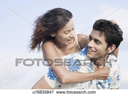 Stock Photo - Close-up of a young woman riding piggyback on a young man. Fotosearch