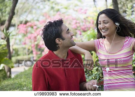 Close-up of a young woman standing with a young man and listening to music View Large Photo Image Stock Image - Close-up of a young woman standing with a young man and listening to music. Fotosearch