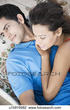 Stock Image - High angle view of a young couple lying in a hammock. Fotosearch