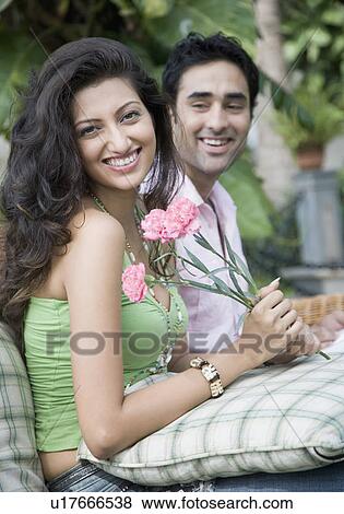 Stock Photo - Portrait of a young couple sitting together and smiling. Fotosearch