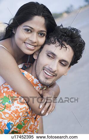 Portrait of a young woman riding piggyback on a young man and smiling View Large Photo Image Stock Photography - Portrait of a young woman riding piggyback on a young man and smiling. Fotosearch