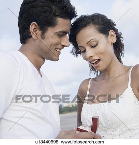 Side profile of a young man gifting a ring to a young woman View Large Photo Image Stock Photo - Side profile of a young man gifting a ring to a young woman. Fotosearch