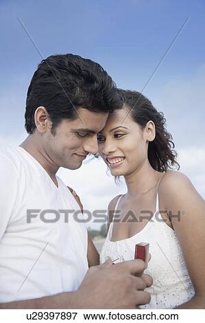 Stock Photo - Side profile of a young man gifting a ring to a young woman. Fotosearch