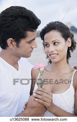 Side profile of a young man giving a flower to a young woman View Large Photo Image Stock Photo - Side profile of a young man giving a flower to a young woman. Fotosearch