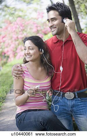 Young couple listening to music on an MP3 player and smiling View Large Photo Image Stock Image - Young couple listening to music on an MP3 player and smiling. Fotosearch