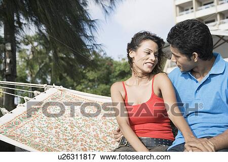 Young couple sitting in a hammock and looking at each other View Large Photo Image Stock Photo - Young couple sitting in a hammock and looking at each other. Fotosearch