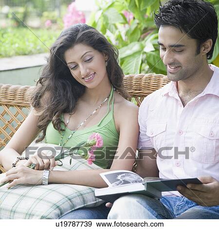 Young couple sitting on a couch and reading a book View Large Photo Image Stock Photo - Young couple sitting on a couch and reading a book. Fotosearch