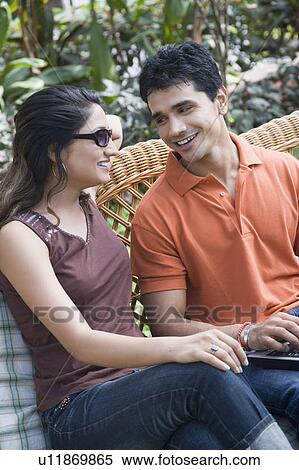 Young couple sitting on a couch and smiling View Large Photo Image Stock Photography - Young couple sitting on a couch and smiling. Fotosearch