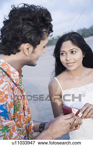 Stock Photo - Young man giving a ring to a young woman. Fotosearch