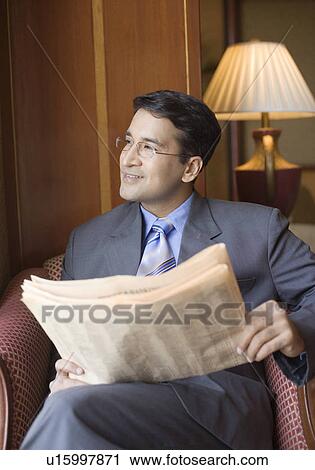 Stock Image - Businessman holding a newspaper and smiling. Fotosearch