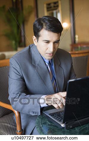 Stock Photo - Businessman sitting in an armchair and working on a laptop. Fotosearch
