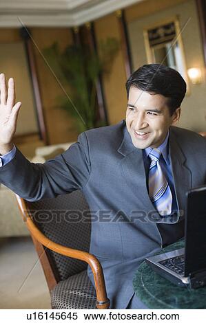 Businessman sitting in an armchair and waving his hand View Large Photo Image Stock Photography - Businessman sitting in an armchair and waving his hand. Fotosearch