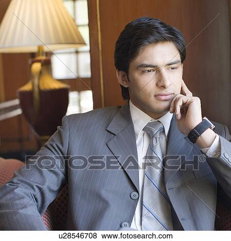 Stock Photo - Businessman sitting with his hands on his chin. Fotosearch