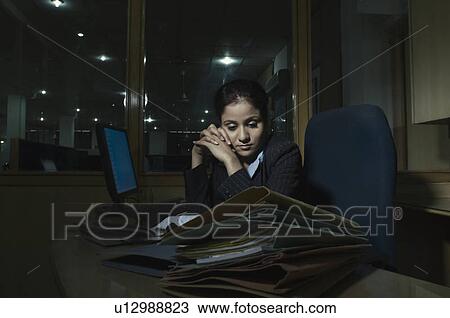 Stock Image - Businesswoman sitting in an office and thinking. Fotosearch