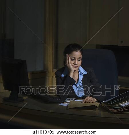 Stock Photography - Businesswoman thinking with her hand on her chin in an office. Fotosearch