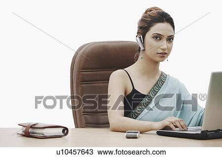 Businesswoman working on a laptop wearing a hands free device View Large Photo Image Stock Image - Businesswoman working on a laptop wearing a hands free device. Fotosearch